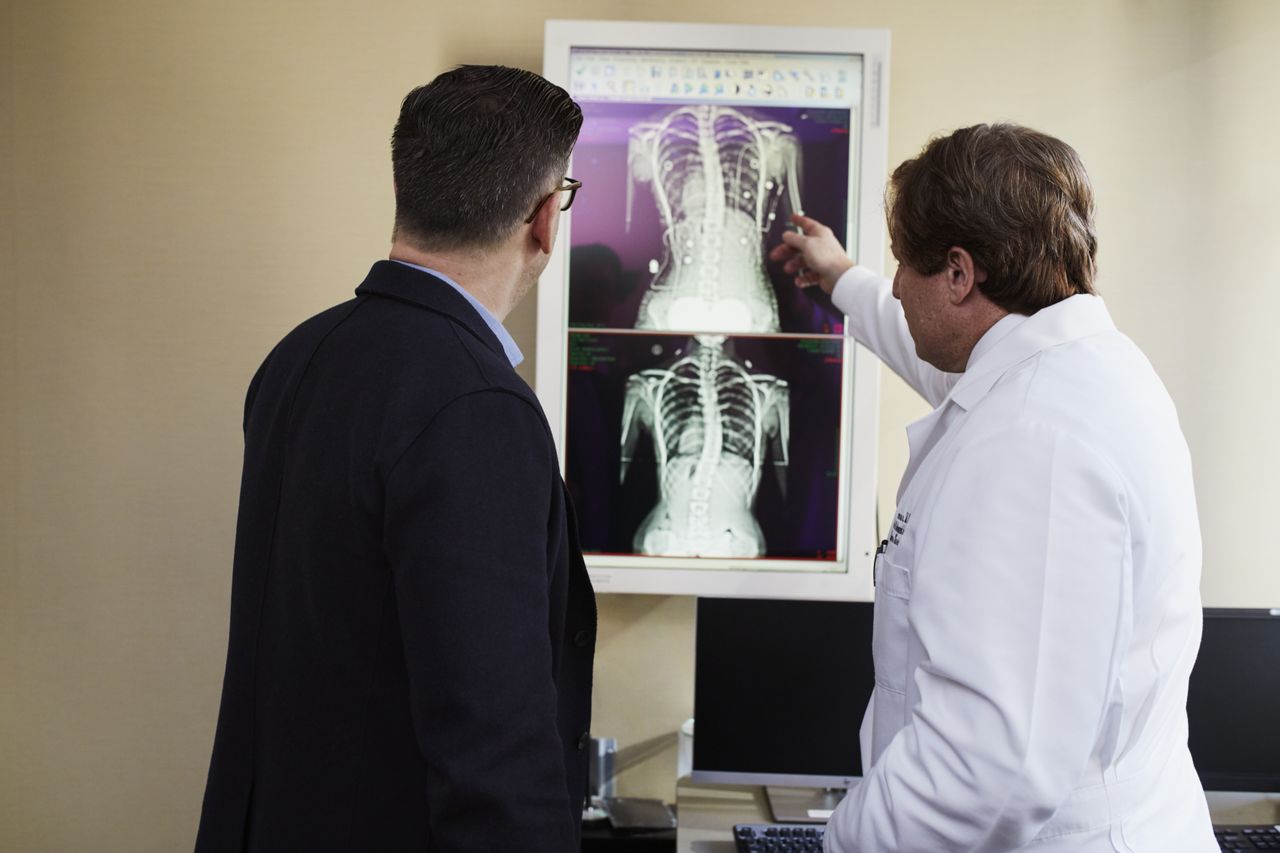 Home A doctor explains X-ray results to a patient in a clinical setting, highlighting healthcare communication.