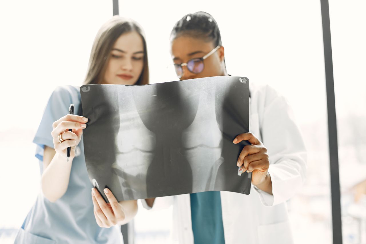 Home Two female doctors reviewing an x-ray image in a bright clinic.